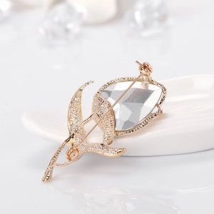 Elegant tulip brooch featuring a faceted crystal and gold-textured leaves on a white ceramic dish