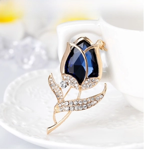 Elegant tulip flower brooch with deep blue crystal and white rhinestones on a white cup