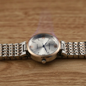 Macro shot of silver watch face with crystal markers and bicolor rose gold band