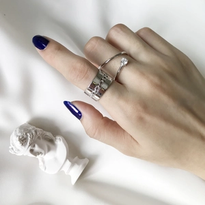 Three-piece silver ring set featuring chain link band and zircon stone on silk fabric