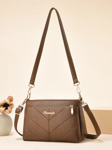 Détail du sac bandoulière marron foncé à texture lychee avec coutures en V et accents dorés