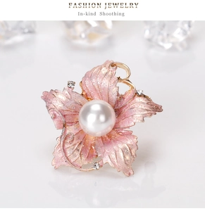 Detail of pink floral brooch with gold edges, glitter petals, and a center pearl inlay
