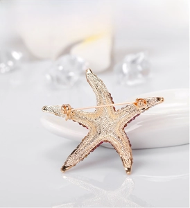 Macro shot of gold starfish brooch back with matte texture and purple gradient rhinestones