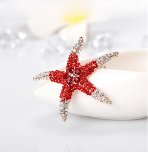 Macro detail of starfish brooch with red and white rhinestones on golden metal base