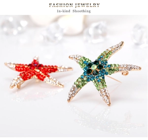 Detail of red and blue starfish brooches with shimmering rhinestones on gold-plated alloy