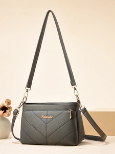 Détail du sac bandoulière gris foncé avec texture litchi, surpiqûres en V et logo doré