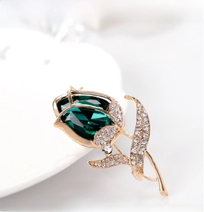 Close-up of tulip flower brooch with large green crystal and white rhinestones