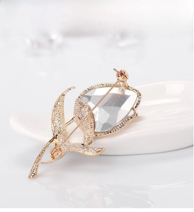 Close-up of golden tulip brooch back showing long needle pin and faceted crystal