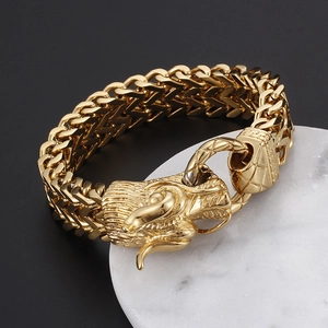 Men's gold keel chain bracelet featuring a detailed dragon head clasp on marble pedestal