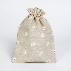 Detail of linen drawstring pouch featuring a white daisy pattern and cotton texture