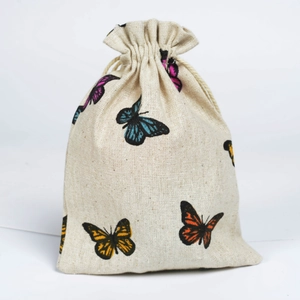 Detailed view of a beige linen drawstring bag with vibrant butterfly prints on white background