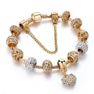 Macro view of gold snake chain bracelet featuring heart charms and crystal beads