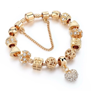 Detail of gold-plated snake chain bracelet with sparkling heart charm and safety chain