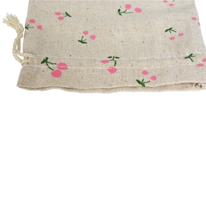 Close-up of beige linen drawstring bag with cherry print and natural hemp rope detail