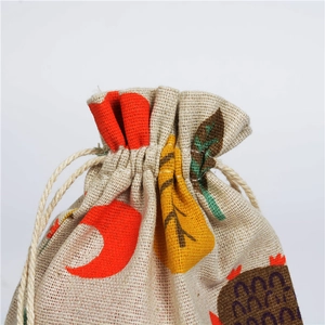 Close-up of linen drawstring pouch featuring autumn leaf patterns and natural rope closure