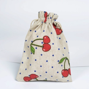 Detail view of cotton linen drawstring bag with red cherry and blue polka dot patterns