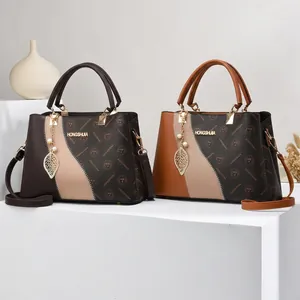 Détail d'un sac à main élégant bicolore en similicuir avec logo et pendentifs en métal