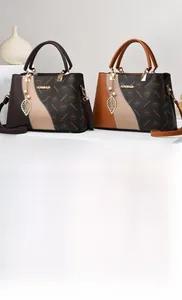 Detail of elegant two-tone faux leather handbag with logo pattern and metal pendant charms