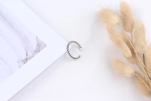 Detail of vintage twisted S925 sterling silver ring on a white fabric with dried flowers