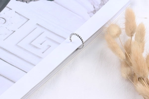 Close-up of S925 sterling silver braided twist ring on a book with dried grass