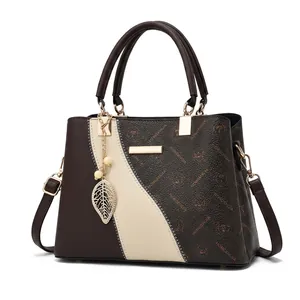Détail du grand sac cabas bicolore en cuir de vache avec breloque logo de la marque