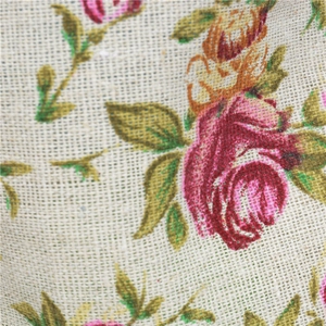 Close-up macro of beige linen fabric texture with red roses and green leaf pattern