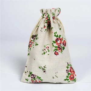 Linen drawstring pouch detail showing red floral and green leaf patterns on white
