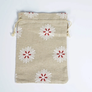 Detail of beige linen drawstring bag featuring a white and red snowflake pattern