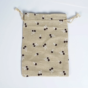 Detail of beige cotton drawstring bag featuring brown cherry print and natural hemp rope