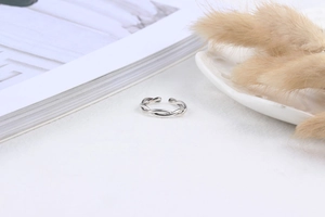 Macro shot of silver twisted braided ring on white fabric with dried flowers and magazine