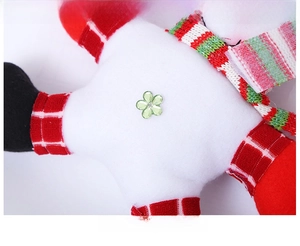 Detail of white plush Christmas ornament with red plaid limbs and a green floral sequin