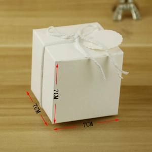 Detailed view of a 7x7x7cm white gift box with rope handle and tag on wood background