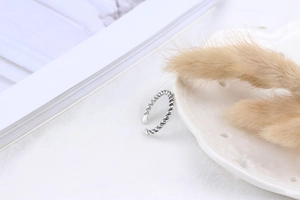 Detailed close-up of S925 sterling silver twisted rope ring on white textured background