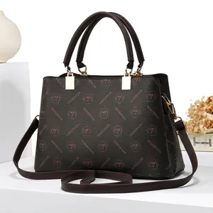 Détail d'un sac à main en cuir marron avec boucles dorées et motifs de logos imprimés