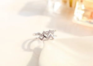 Detail of silver double-layered wavy ring featuring sparkling white crystals and polished finish