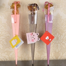 Detailed view of three gold-plated roses in pink, brown and purple cone gift boxes