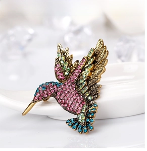Detailed macro view of hummingbird brooch with colorful rhinestones on vintage gold base