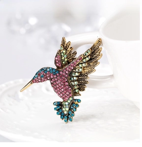 Macro shot of colorful rhinestone hummingbird brooch in vintage gold finish