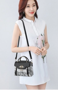 Vue détaillée du sac floral avec boucle cygne dorée et perle sur une robe blanche