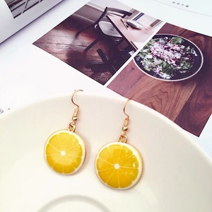 Macro detail of yellow resin lemon slice earrings with gold-toned hooks and trim