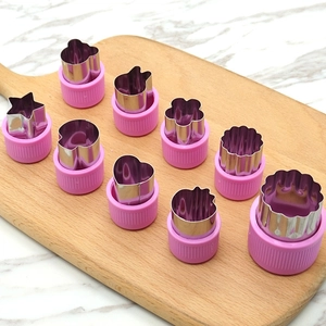 9-piece stainless steel vegetable and fruit cutter set with pink plastic handles on wood