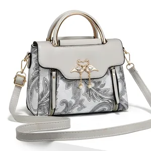 Détail du sac bandoulière gris avec motif paisley et boucle cygne dorée avec perles
