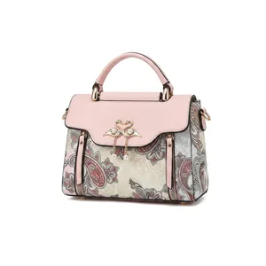 Détail en cuir PU avec motif paisley et pendentif cygne doré sur un sac à main rose