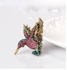 Detailed close-up of a hummingbird brooch featuring colorful rhinestones and vintage bronze finish