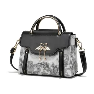 Détail du sac à main vintage avec poignée dorée et logo cygne à côté d'un téléphone