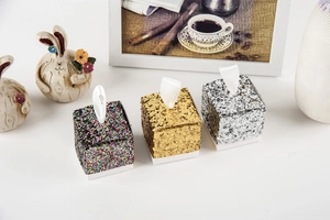 Detail of glitter candy boxes in gold and silver with white satin ribbon handles