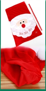 Detailed view of large red plush Santa gift bag with Ho Ho Ho ribbon and embroidered face