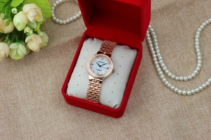 Close-up of elegant rose gold watch with rhinestones in a red velvet luxury gift box