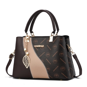 Brown monogram leather handbag with dual handles and gold logo on a white background