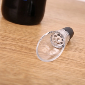 Petal-shaped stainless steel wine aerator pourer on a wooden table with silicone seal